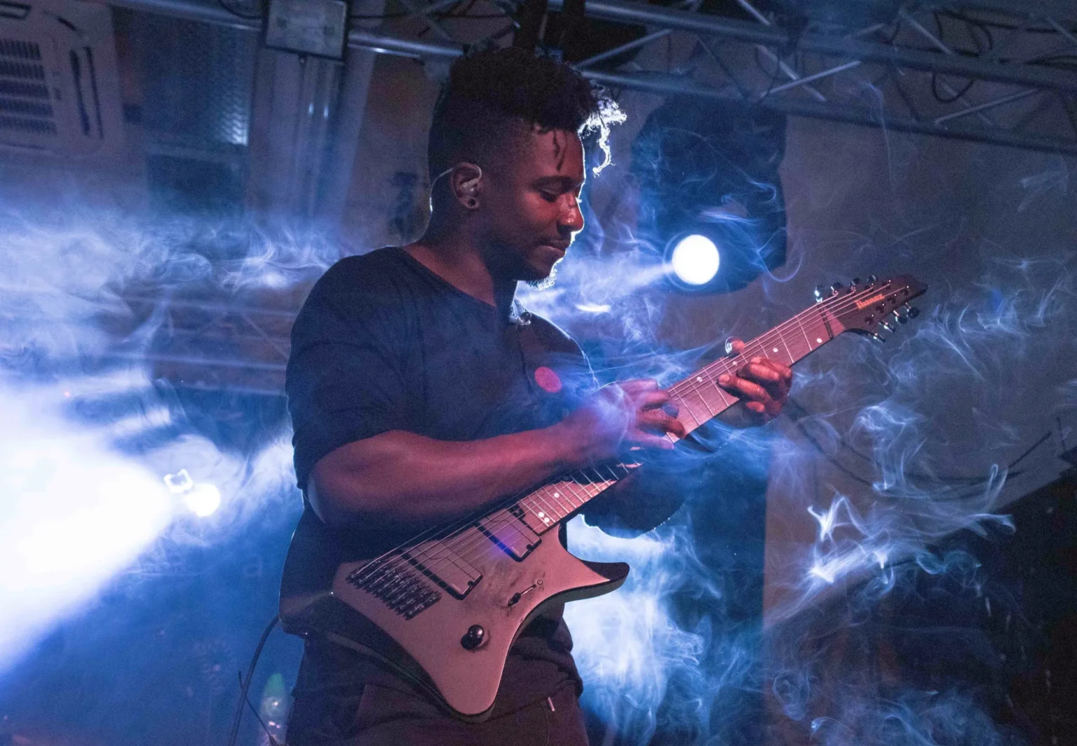 Tosin Abasi gra na gitarze podczas koncertu Animals as Leaders