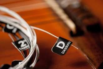 Zbliżenie na komplet strun gitarowych D’Addario z etykietą, na tle pudła rezonansowego gitary klasycznej